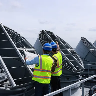Construction team assessing large rooftop fans